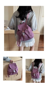 Detail view of purple textured waffle fabric backpack with buckle closure and side pockets