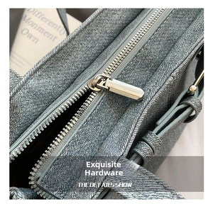 Detail of silver metal zipper and denim texture on a blue bucket bag with fine stitching