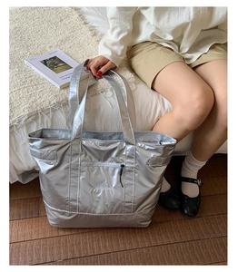 Grand sac cabas argenté métallisé avec poche zippée, mis en scène dans un salon cosy