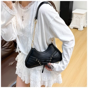 Detail of black ballet-style shoulder bag featuring punk lacing and gold chain strap