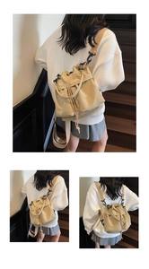 Dettaglio borsa a secchiello in tela beige con tracolla kaki e chiusura a coulisse
