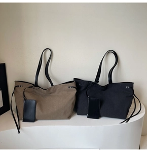 Detail of khaki and black canvas tote bags with leather straps on a modern stand