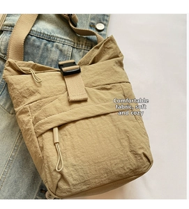 Detalle de bolso bandolera de nailon caqui con hebilla negra sobre chaqueta vaquera