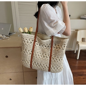 Detail of hollow-out floral weave on straw tote bag with brown leather shoulder straps