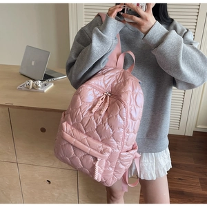 Detail of pink quilted puffer backpack showing metallic luster and braided zipper pull
