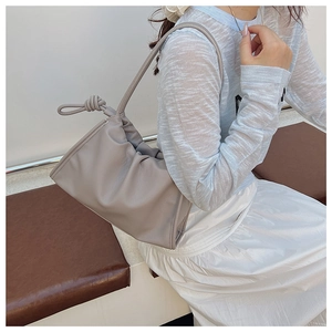 Détail du sac nuage plissé souple taupe avec bandoulière nouée sur un mannequin