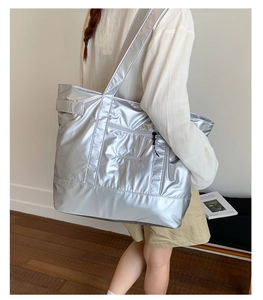 Detail of silver metallic tote bag with embroidery and functional front zipper pocket