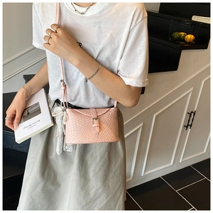 Détail du sac bandoulière rose tissé avec pendentif en perles et dentelle et boucle dorée