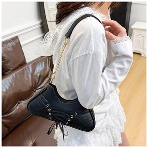 Detail of black crescent hobo bag with lace-up straps and metallic eyelets in Y2K style