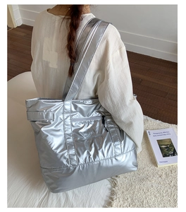 Detail of silver metallic tote bag showing water-resistant texture and front zipper pocket