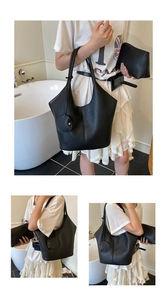 Close-up of black lychee-grain leather tote bag with round pendant and matching pouches