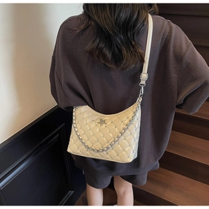 Détail du sac bandoulière beige matelassé avec étoile argentée et chaîne en métal