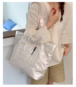 Macro view of metallic silver tote bag featuring high-shine texture and front zip detail