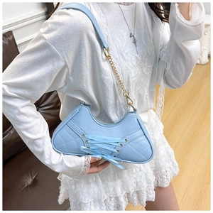 Close-up of light blue bag featuring criss-cross lace-up details and diamond quilting
