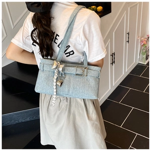 Detail of light blue denim tote bag featuring silver bow charms and heart pendants