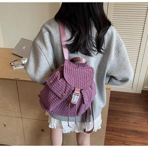 Detail des lila karierten Segeltuch-Rucksacks mit Schnallenverschluss auf einem Schreibtisch