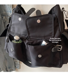 Close-up of black nylon crossbody bag with functional front pockets for easy storage