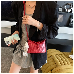 Détail d'un sac seau tissé rouge avec boucle en métal et pendentif en dentelle perlée