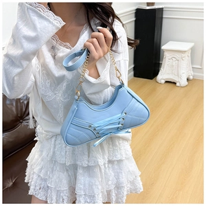 Close-up of light blue handbag with lace-up details, quilting, and gold chain strap