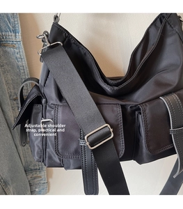 Detail of adjustable shoulder strap and utility pockets on black nylon crossbody bag