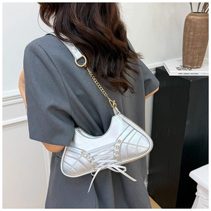 Detail of silver ballet-style shoulder bag with decorative ribbons and chain strap
