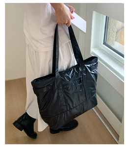 Vue latérale détaillée d'un grand sac cabas noir brillant avec fermeture éclair avant