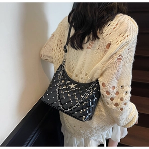 Détail d'un sac porté épaule matelassé noir avec badge étoile argentée et perles blanches
