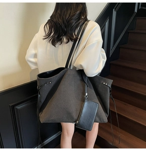 Detail of grey canvas tote bag with black leather straps and hanging zipper pouch accessory