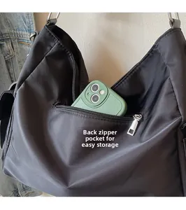 Close-up of functional back zipper pocket on black nylon crossbody bag for easy storage