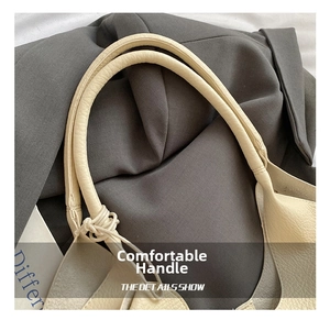 Detail of beige lychee grain leather tote bag showing the knotted handle craftsmanship