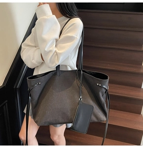 Detail of dark grey canvas tote bag with shoulder strap and matching coin purse on model