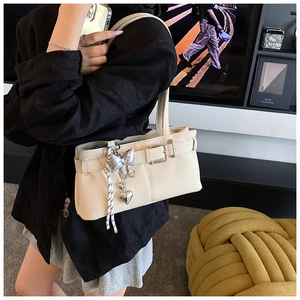Detail of cream bucket bag with silver butterfly heart charm and decorative buckle strap