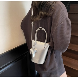 Silver bucket bag with elephant charm shown from behind on a model with strap