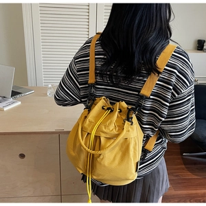 Yellow nylon bucket bag worn as a backpack in a casual lifestyle setting
