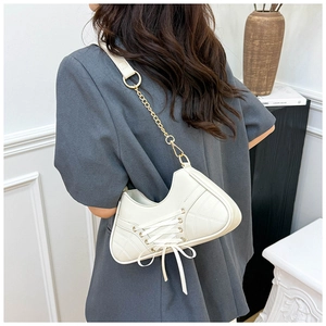 Detail of cream balletcore shoulder bag featuring sneaker-inspired lacing and gold chain