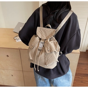 Detail eines karierten Stoffrucksacks mit Kunststoff-Steckschnalle und Kordelzug-Verschluss