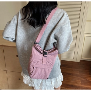 Bolso bandolera de nailon rosa con hebilla mostrado en un entorno real sobre modelo