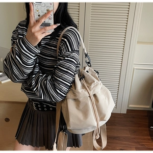Detail of beige nylon multi-way drawstring bag with wide straps and metal hooks
