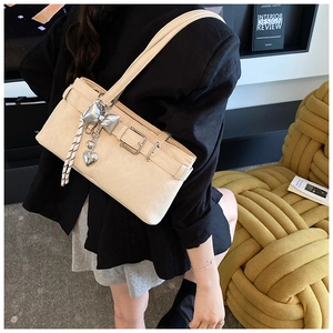 Detail of beige bucket bag with silver bow charm and striped woven rope on modern chair