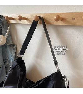 Detail showing the wide fabric shoulder strap and silver metal buckle on a black tote bag