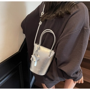Detail of silver bucket bag with knotted shoulder strap and elephant charm on model