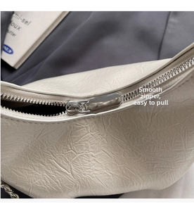 Detail of smooth silver zipper and pleated cream leather texture on luxury handbag