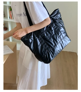 Détail du grand sac cabas noir matelassé avec rembourrage horizontal et logo brodé sur le devant