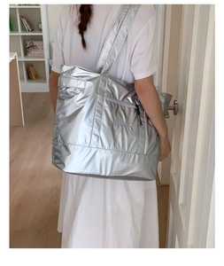 Détail du sac cabas métallisé argenté montrant la large bandoulière et la surface texturée