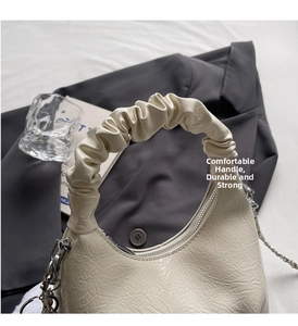 Detail of cream ruched leather handbag with silver chain and pleated handle on grey blazer