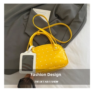 Dettaglio borsa bowling in pelle lucida gialla con cuori e tracolla rimovibile