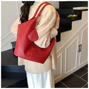 Close-up of red lychee texture tote bag with matching round coin purse on a model