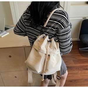 Vista dettagliata della chiusura a coulisse e della tracolla della borsa beige