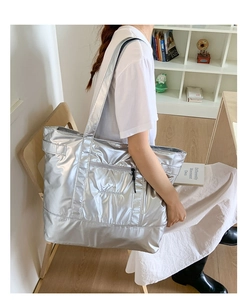 Detail of silver metallic tote bag featuring cursive logo embroidery and long shoulder strap