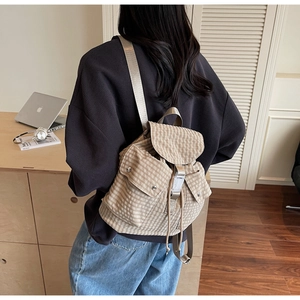 Detail view of a beige gingham backpack featuring a metal buckle pocket and vintage style